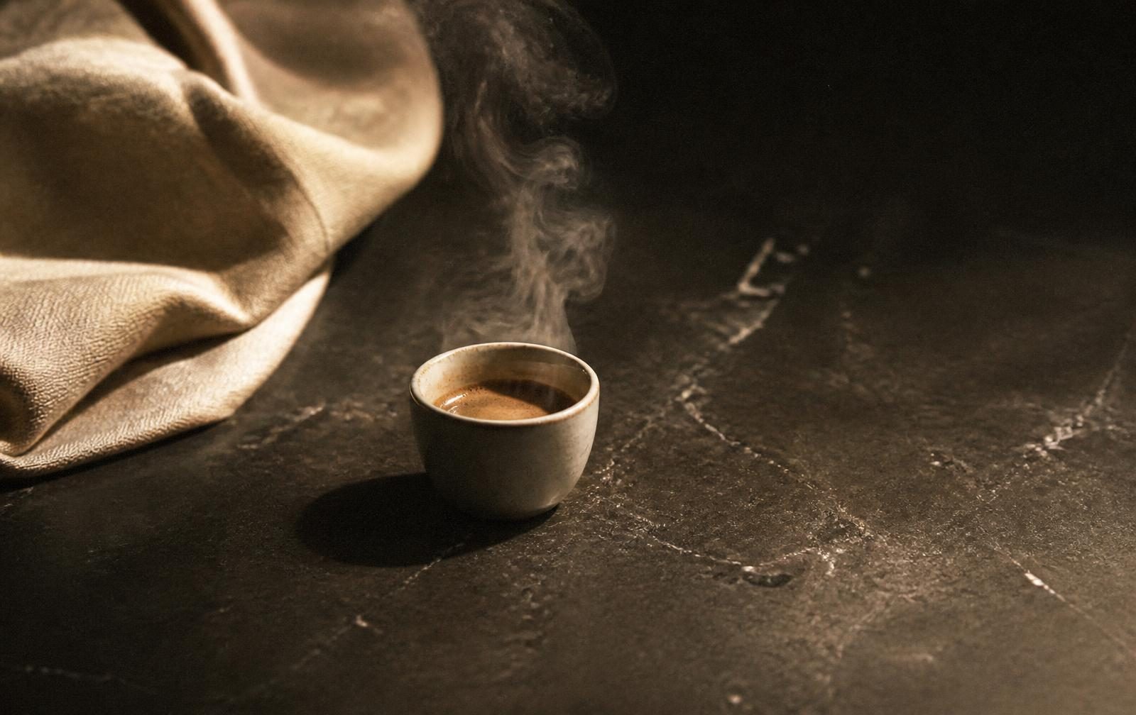 Espresso cup steaming on dark stone
